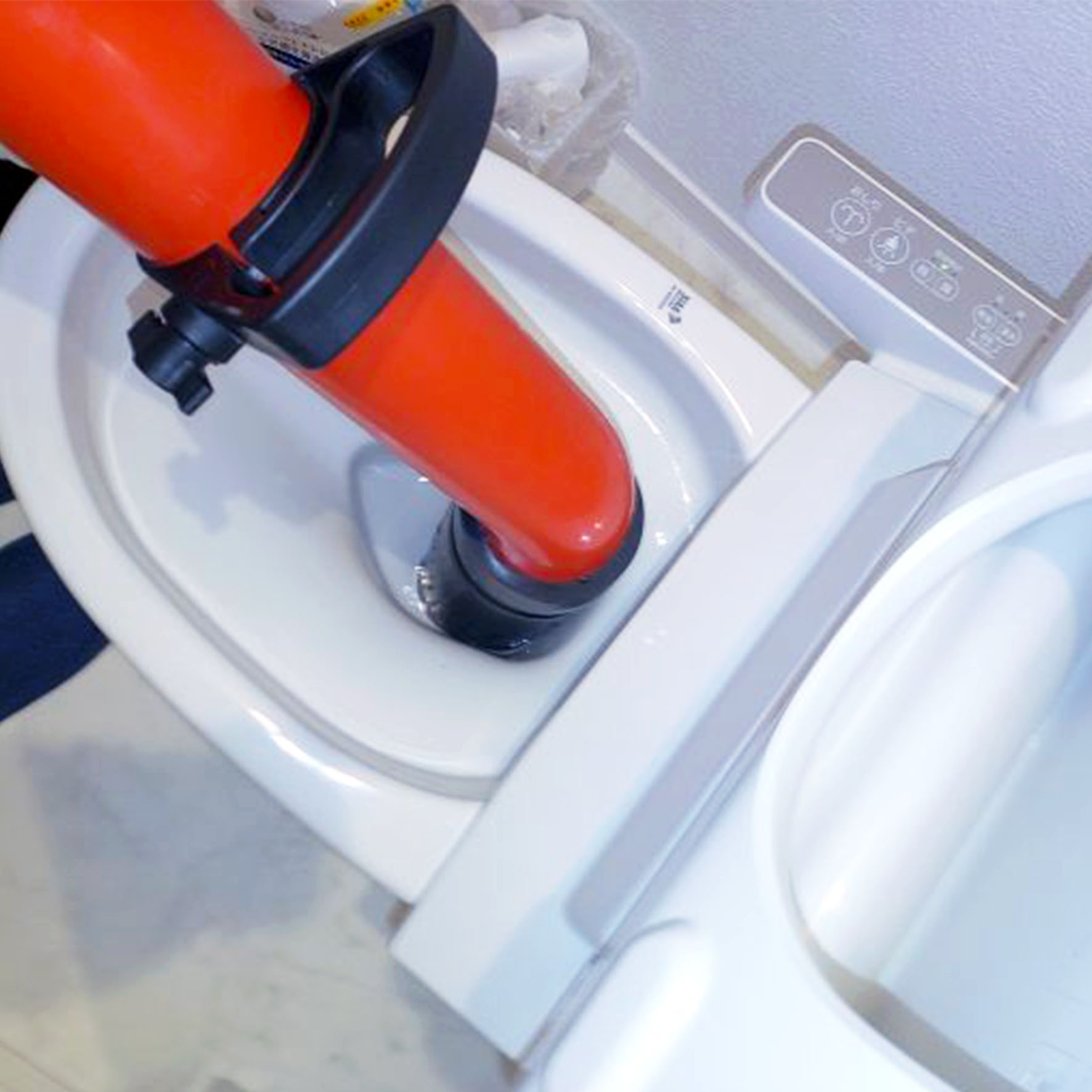 作業中：高圧ポンプを使用してトイレつまりを除去している作業の様子